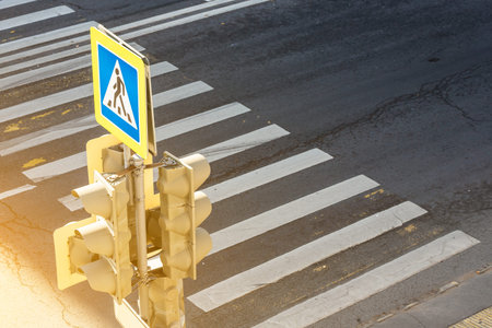 Traffic lights over urban intersection. a traffic light with a pedestrian crossing sign lights up in the city, under the setting sunの写真素材