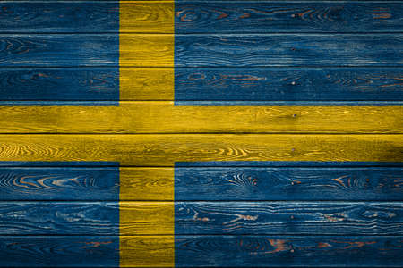 The national flag of Sweden is painted on a camp of even boards nailed with a nail. The symbol of the country.の写真素材
