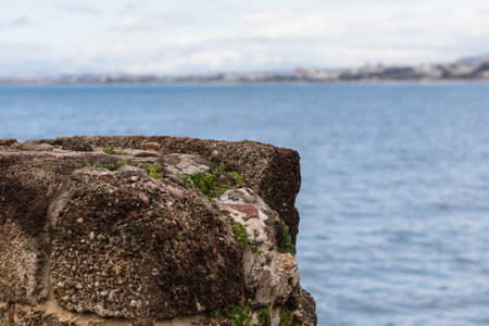 Large stone cliff with a beautiful texture on the background of a sea sunset. Evening landscape on a rocky seashore.の写真素材