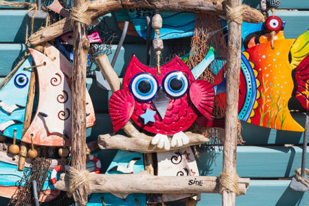 Souvenirs, multi-colored clay figurines, a cat, an owl, ships with seagulls stand in a row for sale in a storeの写真素材
