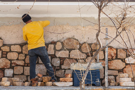 Male professional bricklayer laying out the wall with new stone using a spatulaの写真素材