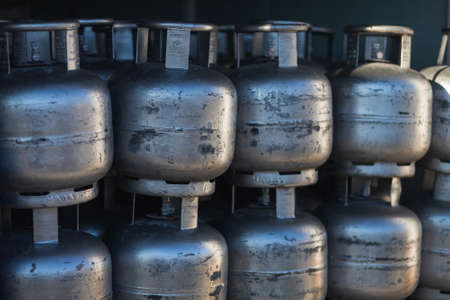 close-up of silvery gas cylinders stand on top of each other in even rows in a warehouseの写真素材