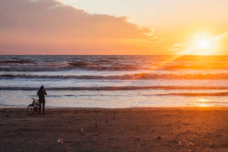 cyclist takes pictures and enjoy the sunset over the sea with a beautiful horizon. wonders of nature. Beautiful landscape of the winter sea.の写真素材