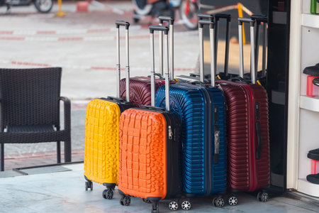 Bright blue, red, yellow and orange rows of suitcases with extended handles and different sizes are...