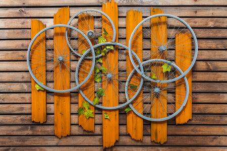 Close-up decorative panel on a wooden wall consisting of bicycle wheels and planksの写真素材