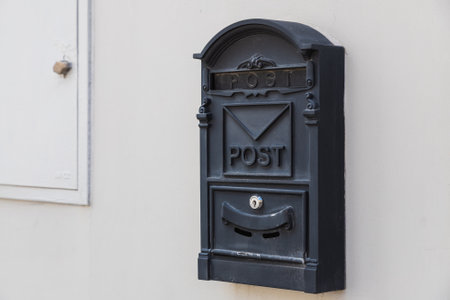 Close-up of a black metal mailbox on a white stone buildingの写真素材