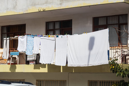 Close-up on a rope, freshly washed white linen, a towel, hairdressing shirts and other things are...