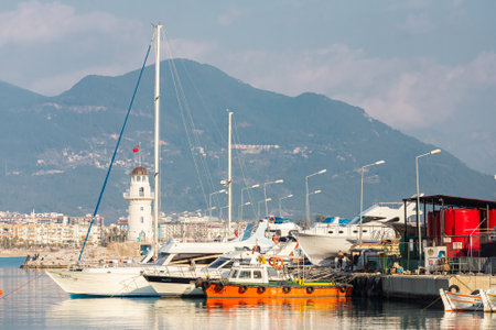 Alanya, Turkey â February 16 2022: Wooden boards of boats, painted white and brown, moored to the pier with ropes against the background of sea water.のeditorial素材