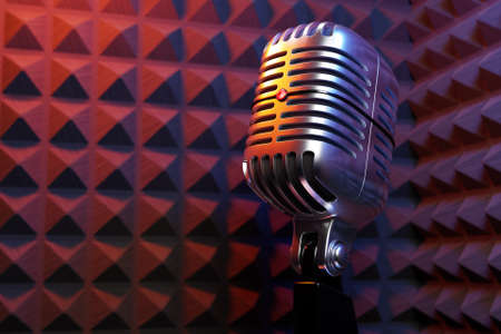 Silver retro microphone against the backdrop of the walls of a recording studio with good sound insulation . minimal style. 3d renderingの写真素材