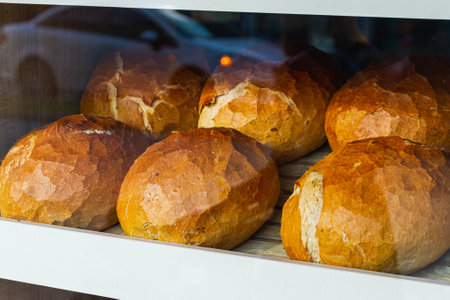 Close-up of fresh white bread in rolls stands in even rows in a bakeryの写真素材