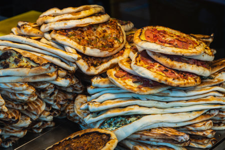 Turkish pizza with butter on the showcase of the cafe. Pizza with baked tomato sauce, meat, mushrooms and herbsの写真素材