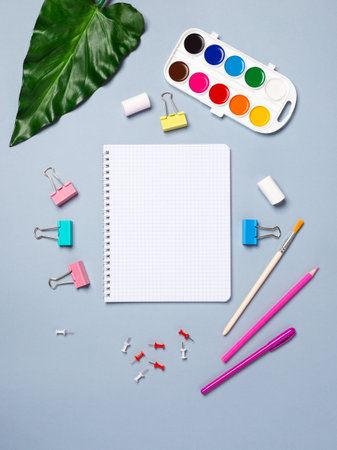 Flat lay office desk with a blank page of a notebook with a pen, pencils, watercolor and other stationery. Top view, flat lay.の写真素材