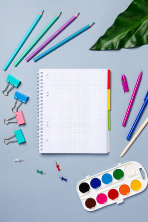 Flat lay office desk with a blank page of a notebook with a pen, pencils, watercolor and other stationery. Top view, flat lay.の写真素材