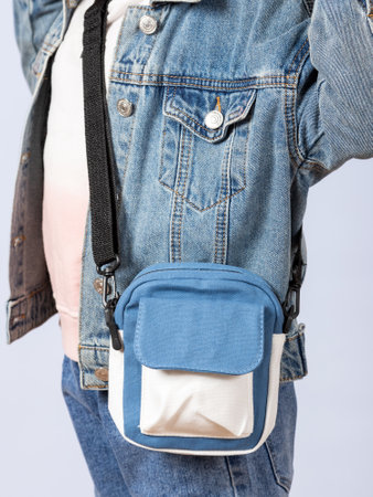 Close-up of a little girl in a denim jacket with a cute shoulder bag in the studio.の写真素材