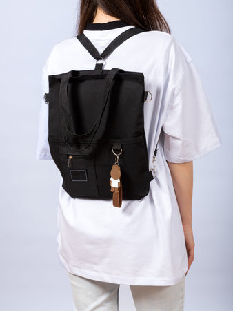 Back of woman with black backpack against white background