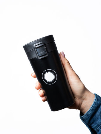 To go coffee cup, smoothie. A woman holds in her hand a reusable mug and a glass of black color made...