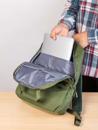 Close-up of a young male student taking out a laptop from a backpack.の写真素材