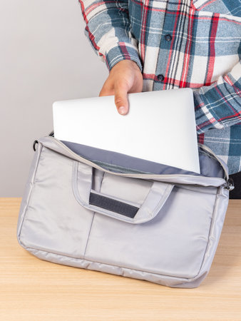 Close-up of a young male student taking out a laptop from a bag.の写真素材