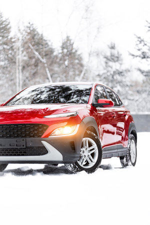 A modern red four-wheel drive SUV is parked on the side of a winter road. Close-up of a car on a...