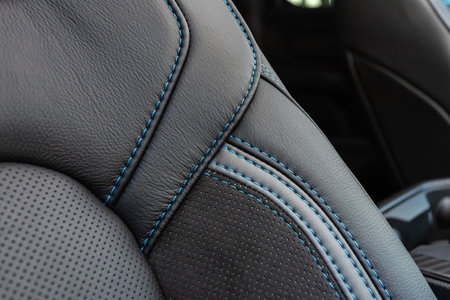 Part of leather car headrest seat details. Close-up black and blue perforated leather car seat. Skin...