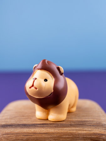 Close-up of small, cute figurines of an adorable lion with a brown mane, placed on a wooden podiumの写真素材