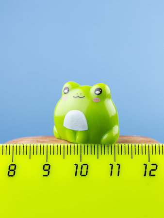 Close-up of a small, cute cartoon-style frog figurine on a wooden podium