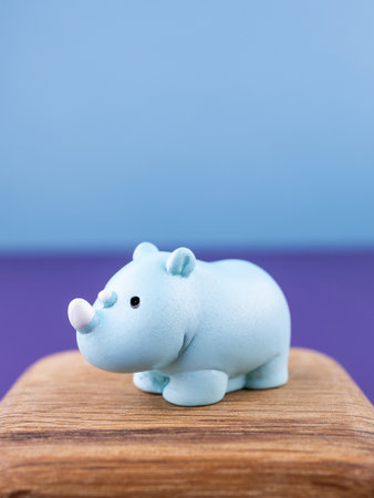 Close-up of small, cute figurines of a blue cartoon rhinoceros, placed on a wooden podiumの写真素材
