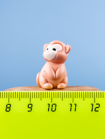 Close-up of small, cute figurines of a brown cartoon monkey, placed on a wooden podiumの写真素材