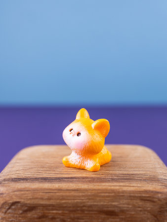 Close-up of small, cute figurines of an adorable orange kitten with a white face, placed on a wooden podiumの写真素材
