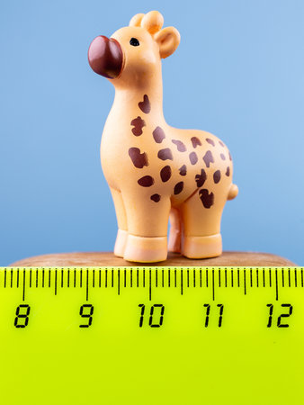 Close-up of small, cute figurines of a lovely giraffe with brown spots, placed on a wooden podiumの写真素材