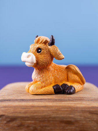 Close-up of a small, cute figurine in the shape of a brown cow, placed on a wooden podium.の写真素材