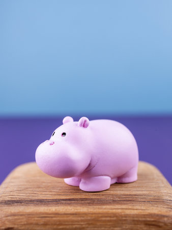 Close-up of small, cute figurines of a pink cartoon animal, placed on a wooden podiumの写真素材