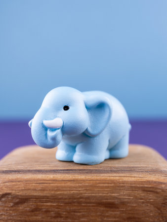 Close-up of small, cute figurines in the shape of an adorable blue elephant, placed on a wooden podiumの写真素材