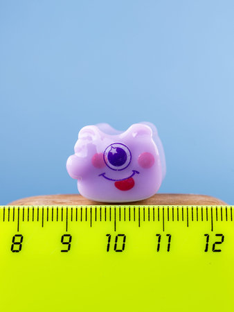 Close-up of a small, cute monster figurine in the form of a puzzle, placed on a wooden podium.の写真素材
