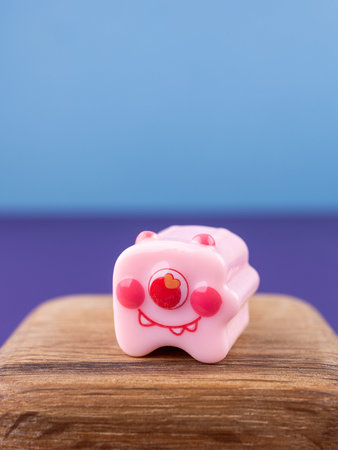 Close-up of a small, cute monster figurine in the form of a puzzle, placed on a wooden podium.