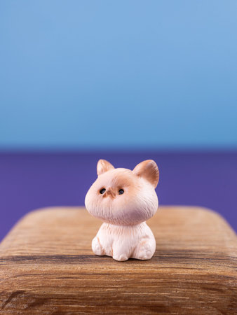 Close-up of small, cute figurines of an adorable white kitten, placed on a wooden podium.