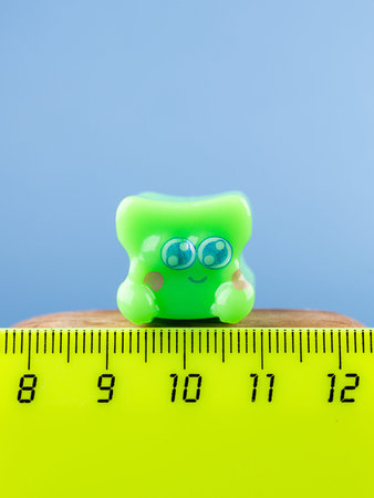 Close-up of a small, cute monster figurine in the form of a puzzle, placed on a wooden podium.の写真素材