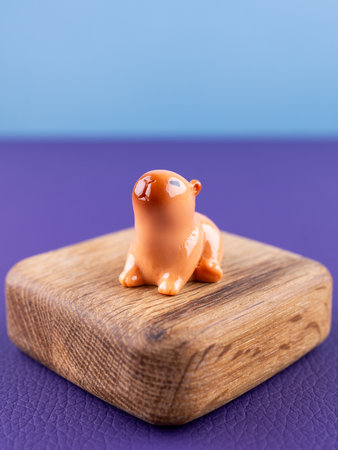 Close-up of a small, cute figurine in the shape of a brown capybara, placed on a wooden podium.の写真素材