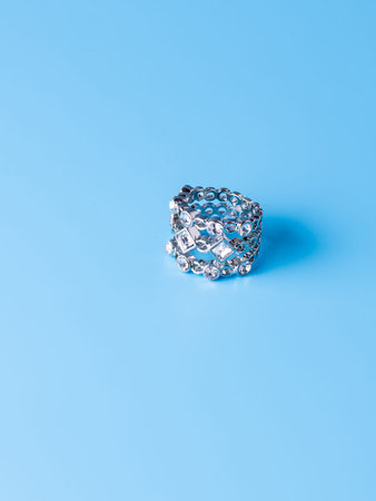 Close-up of a silver ring with white rhinestones against a blue background