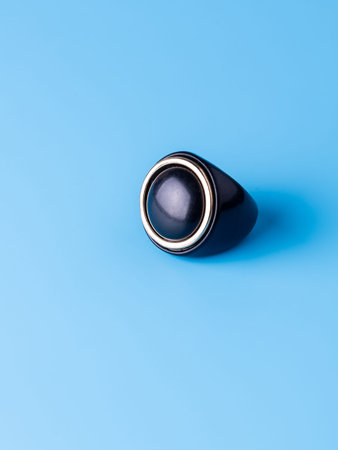 A close-up of a black, distressed ring against a blue background.