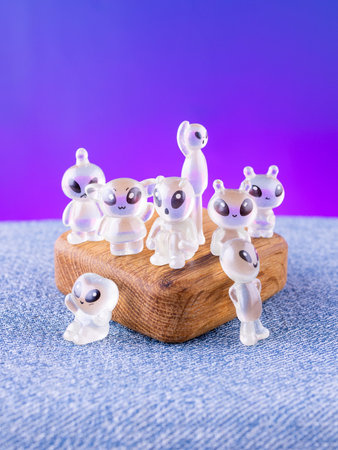 A close-up of a set of miniature transparent, playful extraterrestrial figurines arranged on a wooden stageの写真素材