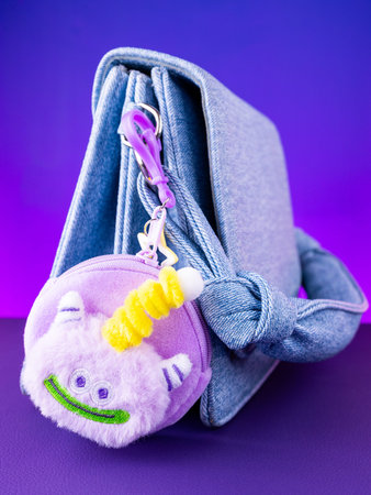 A close-up of a soft purple plush wallet featuring a fun and adorable monster design