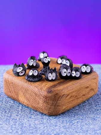 A close-up of a set of miniature interior figurines of black Susuwatari (soot sprites) placed on a wooden stageの写真素材