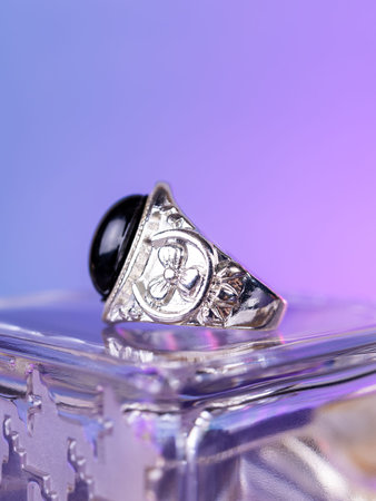 Close-up of a silver ring with a large black stone  against a purple background