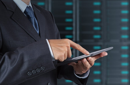 businessman hand using tablet computer and server room background
