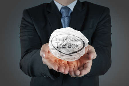 hand shows crumpled paper and think outside the box as conceptの写真素材