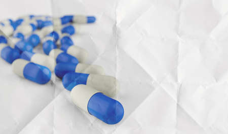 Pills spilling out of pill bottle on crumpled paper as conceptの写真素材