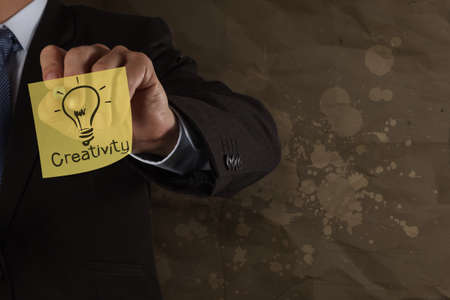 businessman hand draw creativity on sticky note with splash crumpled recycle backgrpund as concept の写真素材