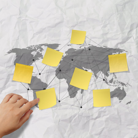 hand pushing sticky note social network icon on crumpled paper background as conceptの写真素材