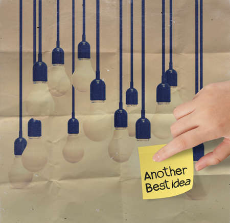 hand touch sticky note with another idea light bulb on crumpled paper as creative conceptの写真素材